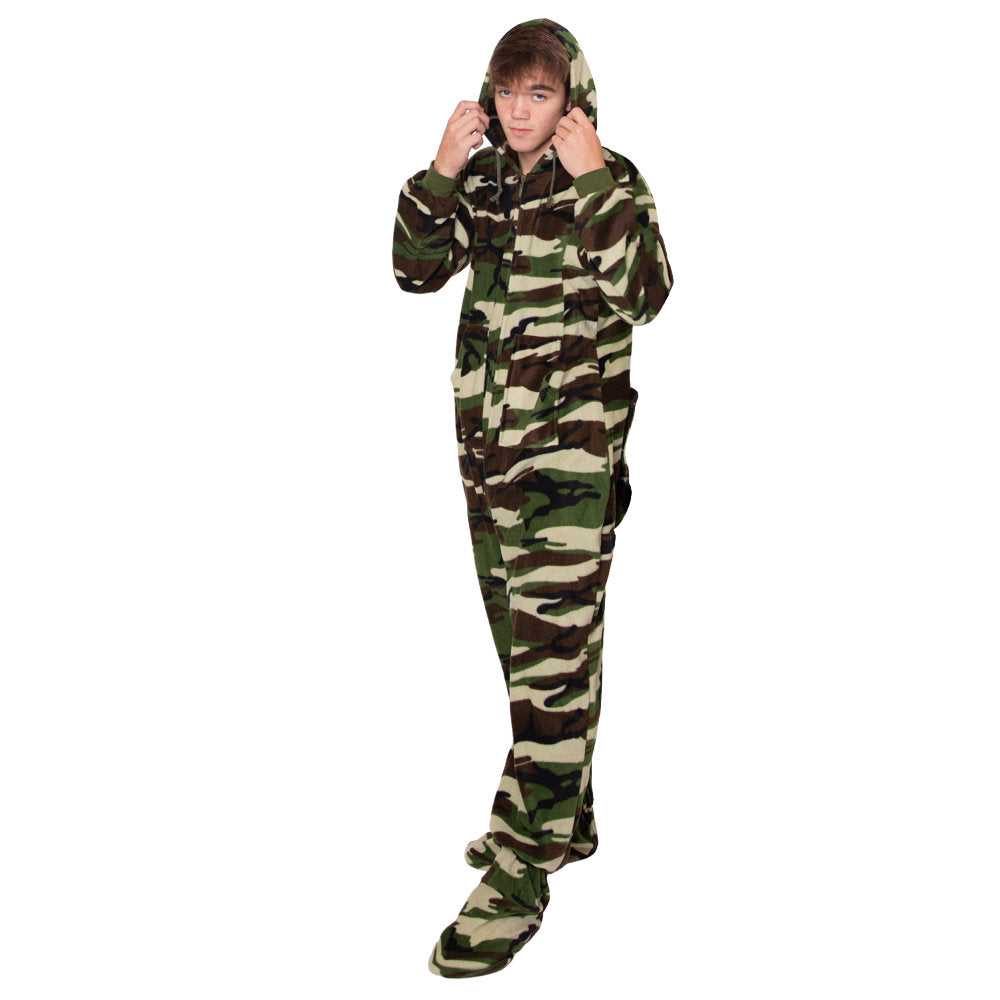 A young man wearing Green, Tan, and Brown Camouflage Fleece Adult Onesie Hoodie Footed Pajamas from Big Feet Pjs.