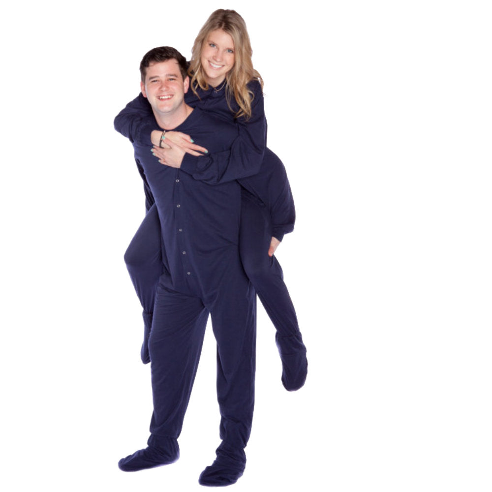 A man giving his wife a piggy-back ride, both wearing matching Navy Blue Cotton Knit Adult Onesie Footed Pajamas for Men & Women from Big Feet Pajama Company.