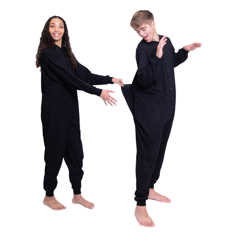 A couple wearing matching Black Cotton Knit Adult Footless Onesie Pajamas for Men & Women she is pulling on his drop seat