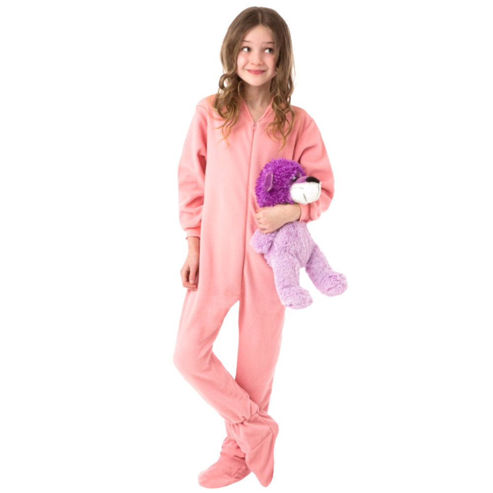 A girl with the cutest grin holding her bear and wearing her new Christmas PJs, Pink Fleece Onesie Footie Pajamas for kids from Big Feet Pajama Company.