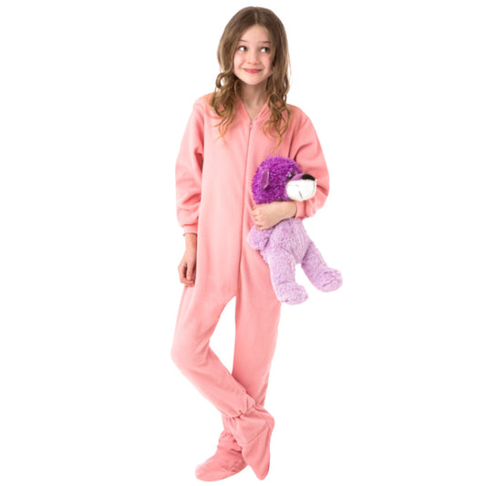 A girl with the cutest grin holding her bear and wearing her new Christmas PJs, Pink Fleece Onesie Footie Pajamas for kids from Big Feet Pajama Company.
