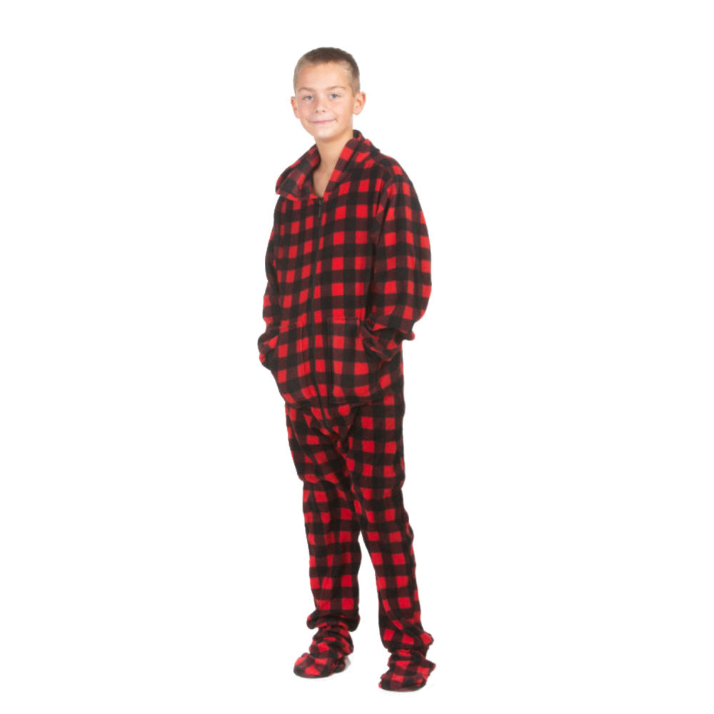A boy is wearing one-piece pjs from the Big Feet Pajama Company line of comfy, fleece footed onesies that make getting ready for bed and relaxing at home easy. This outfit is made of red & black buffalo plaid fleece, and he is posing with his hands in the kangaroo pockets.