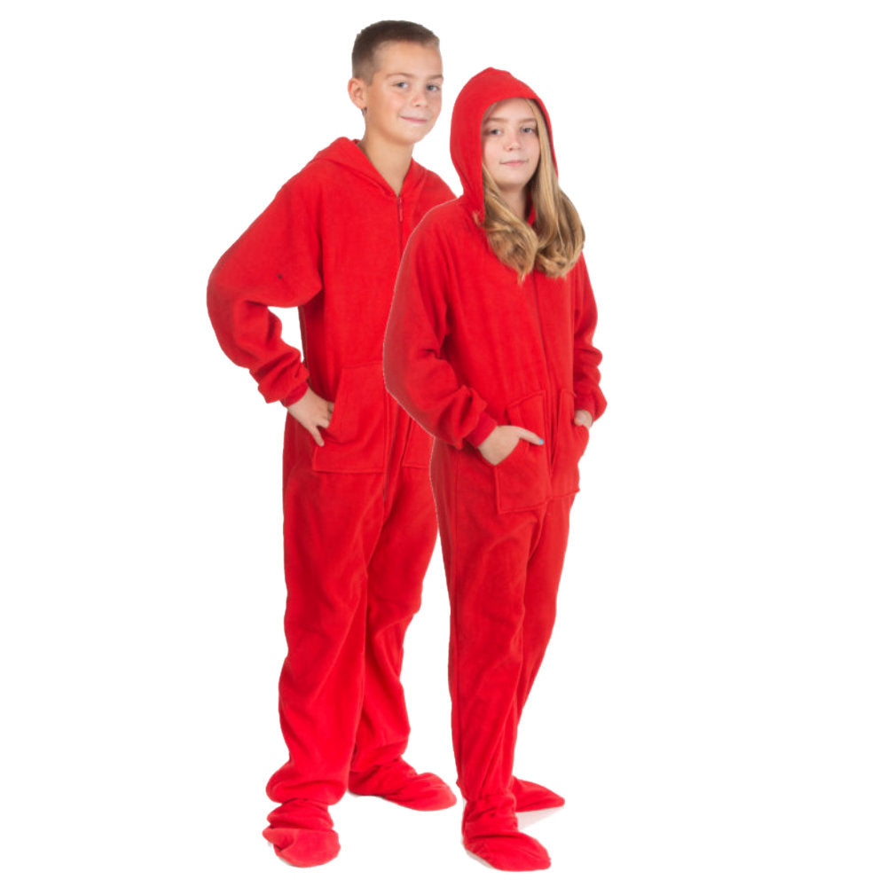 Brother & sister posing for Christmas pictures wearing red fleece hoodie footed onesie pajamas from the Big Feet Pajama Company. She has her hood on with her hands in the kangaroo pockets.