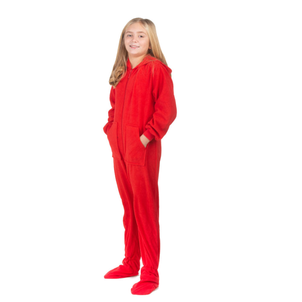 A young girl, wearing one-piece pjs from the Big Feet Pajama Company line of comfy, fleece footed onesies that make getting ready for bed and relaxing at home easy. This outfit is made of red fleece and she is posing with her hands in the kangaroo pockets.