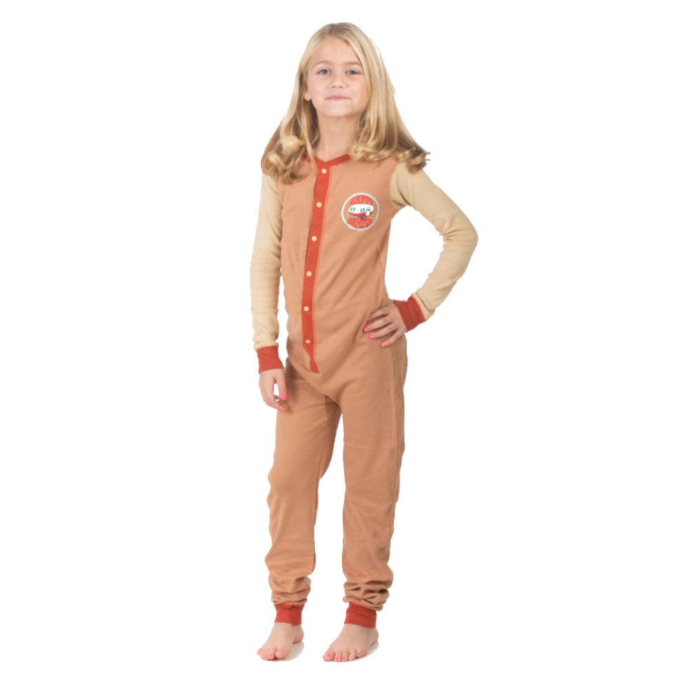 A young girl wearing a brown and beige onesie from the Big Feet Pajama collection of 100% cotton Union Suit Sleepwear and Playwear. The onesies feature a "Happy Camper" badge on the chest. The onesies have long sleeves, cuffs, a snap-up front, and a decorative rear flap with the Happy Camper Bear and Moose by the fire at their campsite.
