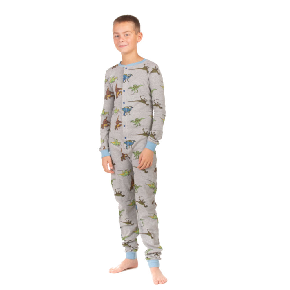 A teen boy wearing cotton footless onesies from Big Feet Pajama Company with five different realistic dinosaurs printed all over them.