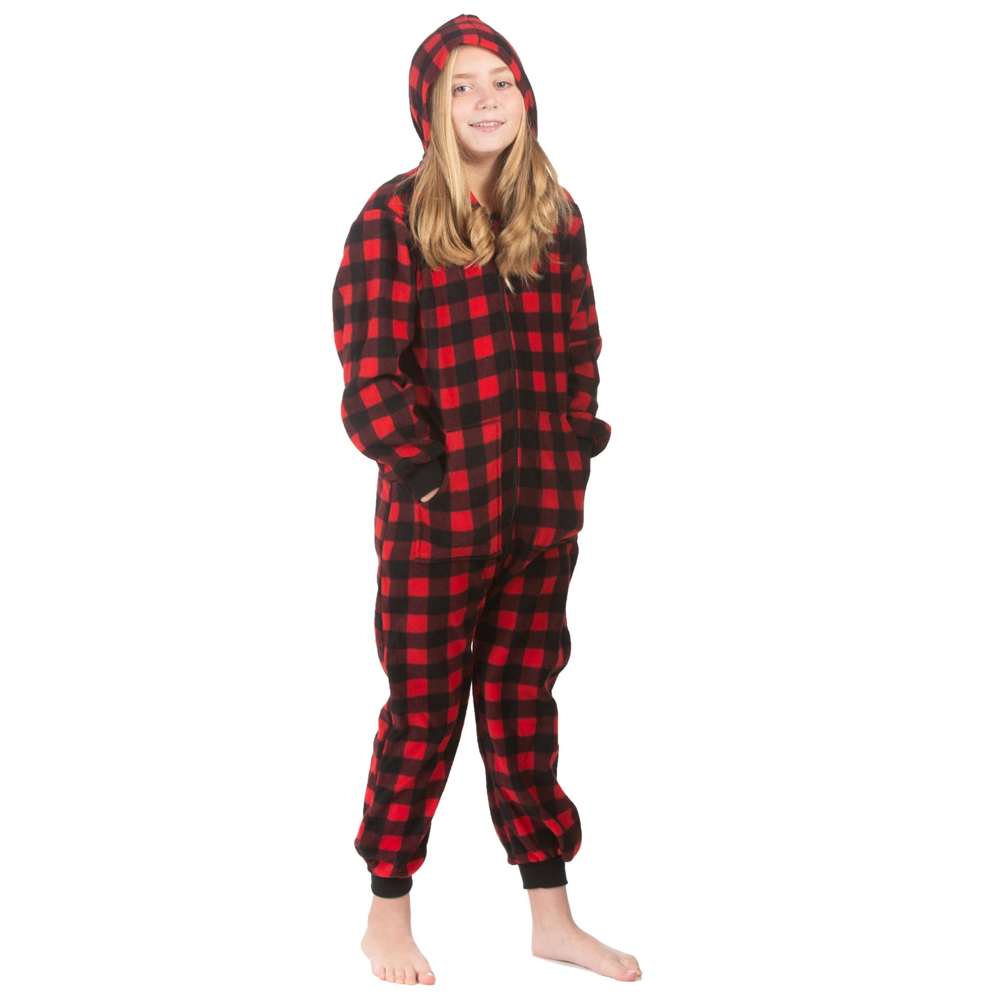 A teen girl is posing for Christmas pictures. She has the hood up and her hands in the kangaroo pockets of her red & black buffalo plaid fleece hoodie non-footed onesie jumpsuit pajamas from the Big Feet Pajama Company.