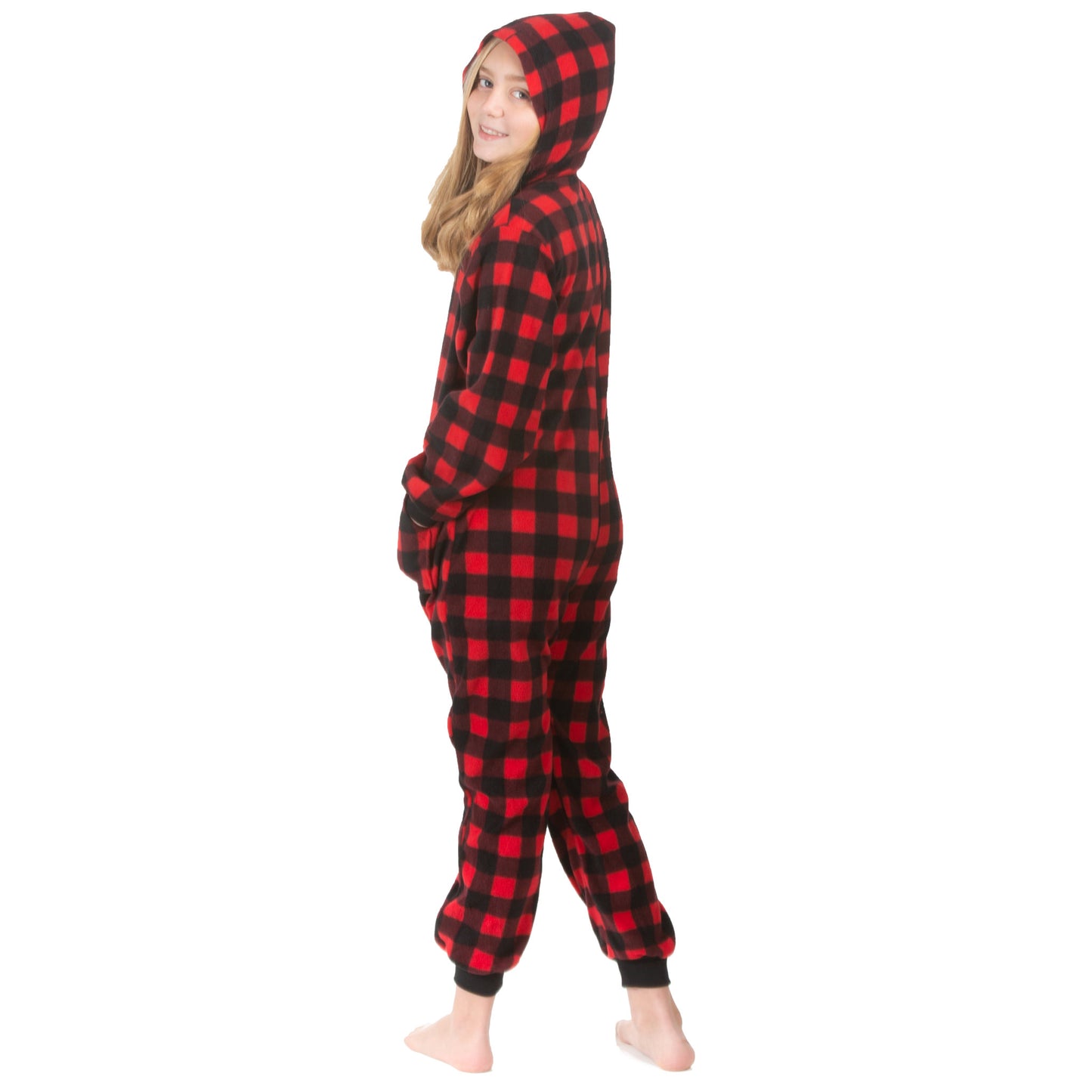 A young girl, wearing one-piece pjs from the Big Feet Pajama Company line of comfy, fleece jumpsuit onesies that make getting ready for bed and relaxing at home easy. This outfit is made of fleece, with the pattern being in Red and Black plaid. She is posing with the hood on and her hands in the pockets.