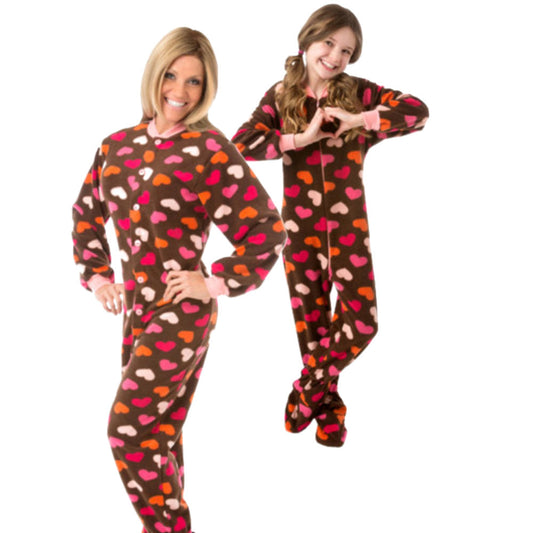 Mother and daughter wearing matching brown fleece onesie pajamas with pink, red and white hearts for Valentine's Day